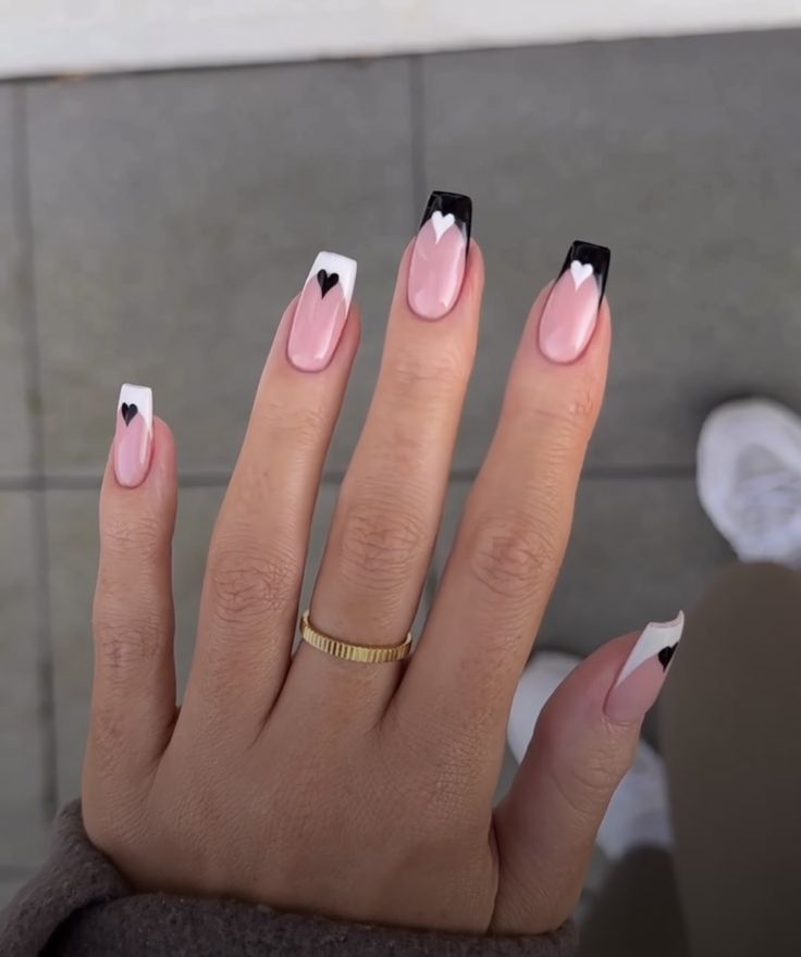 Chic Soft Pink and Black Tip Nail Design with Playful Heart Accents.