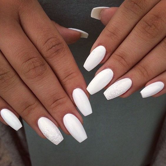 Elegant Glossy White Nail Design with Subtle Shimmer Accents and Sophisticated Elongated Shape.