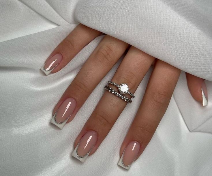 Sophisticated Modern French Manicure with Nude Base, White Tips, and Sparkling Silver Accents.