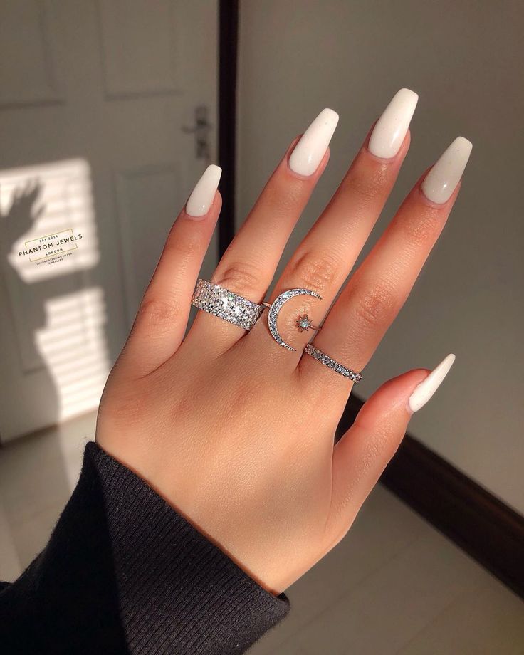 Minimalist Almond-Shaped White Nail Design with Glamorous Jewelry Accents.