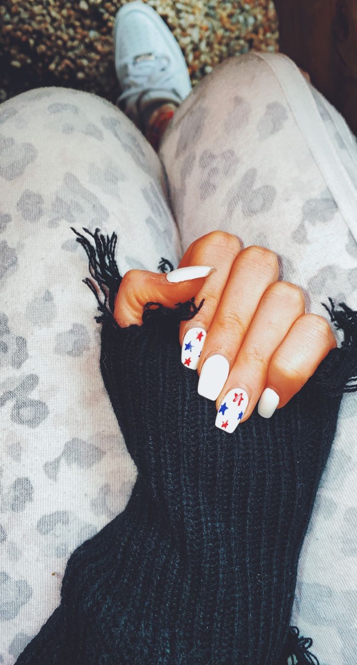 Chic White Nail Design with Playful Red and Blue Stars for Festive Flair.