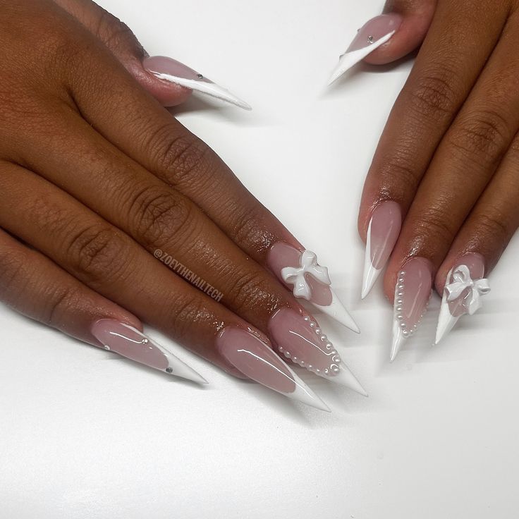 Sophisticated Almond-Shaped Nails with Nude and White Accents Enhanced by Elegant Embellishments.